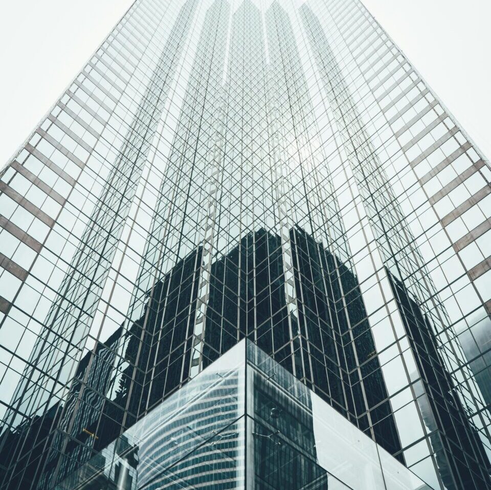 Striking low angle view of a modern skyscraper with reflective glass facade in a cityscape.
