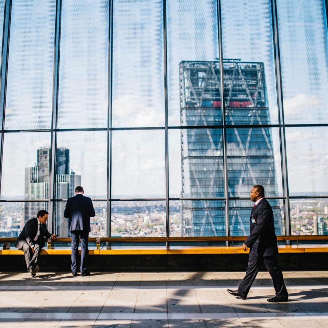 Business professionals in a modern office against a London skyline view.